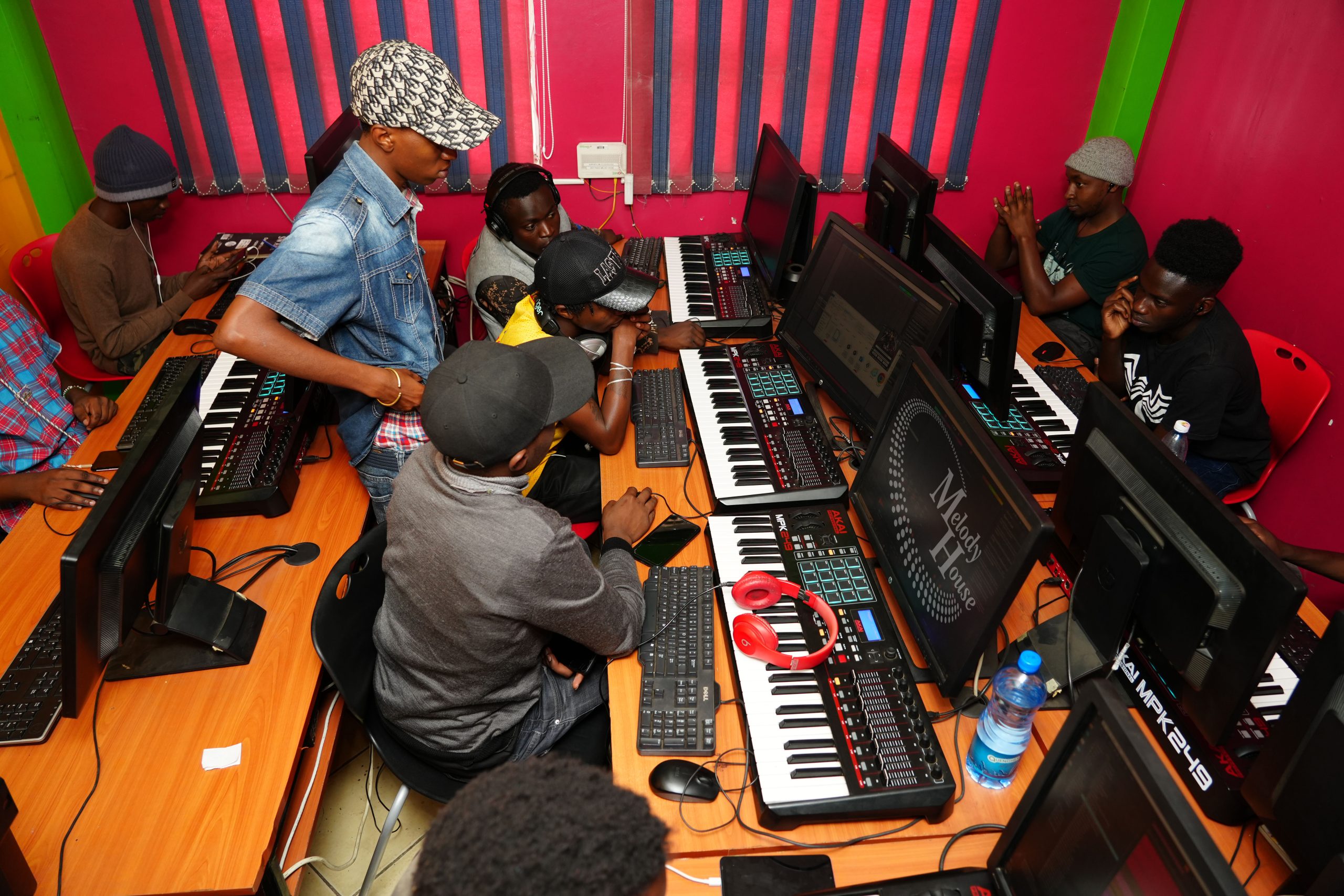 A group of music production students at Music And Film Academy Nairobi working on workstations with Akai MPK249 controllers during a session on music business and royalty registration.
