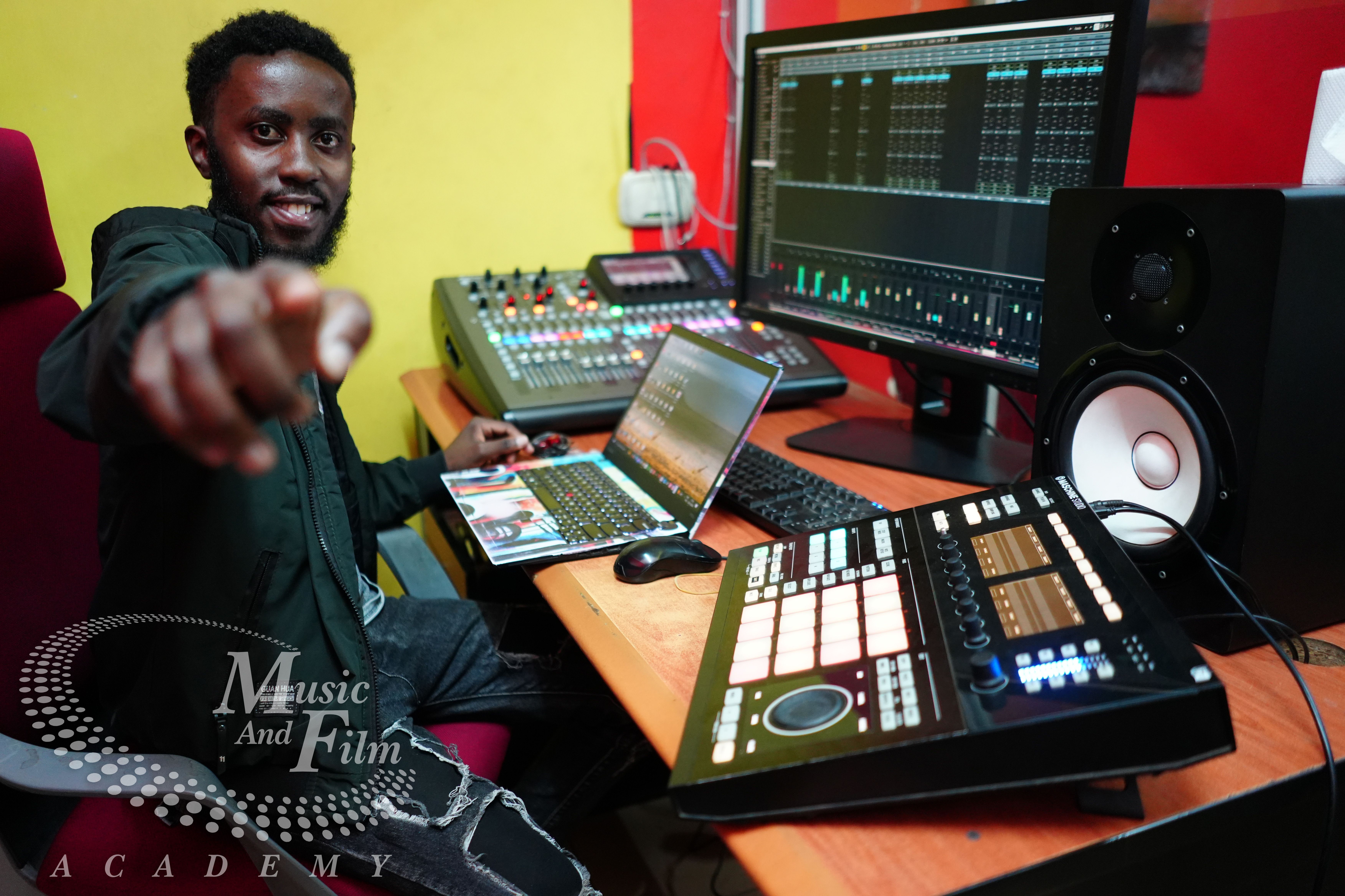 A music production student using a Native Instruments Maschine Studio and digital mixing console in the professional labs at Music and Film Academy, Nairobi.