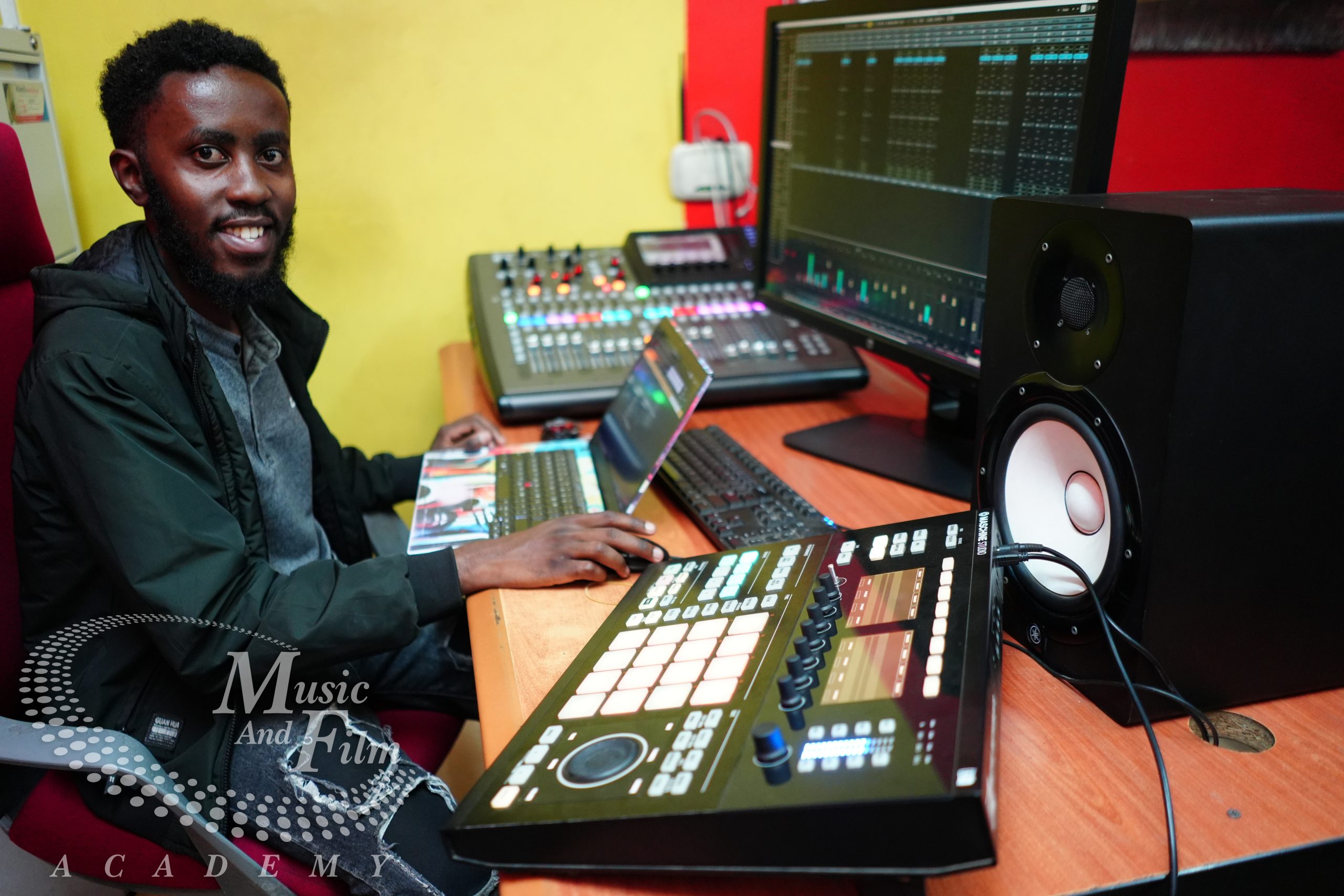 A student producer at Music and Film Academy Nairobi using a Native Instruments Maschine Studio and a digital mixing console for music production.