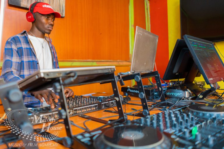 A side-angle shot of a DJ in a red cap using a Pioneer DJ setup at Music And Film Academy Nairobi, demonstrating compliant public performance for the 2026 Kenyan license.
