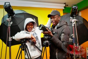 Two videography students at Music and Film Academy Nairobi using a professional Godox softbox setup with a camera on a tripod.