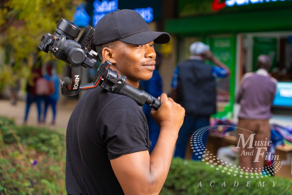 A film student operating a DJI Ronin gimbal stabilizer with a Sony Alpha camera during an outdoor shoot for film production courses in Kenya.