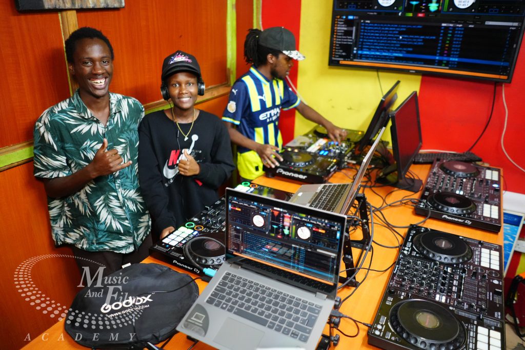 Students at the Music And Film Academy learning advanced DJ mixer techniques, including gain staging and EQ transitions, on industrial Pioneer DJ gear.