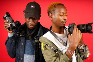 Two photography students comparing focal lengths and lens markings on professional mirrorless cameras during an event shooting lab at Music and Film Academy in Nairobi.