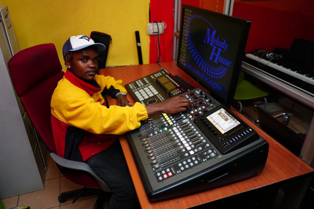 A sound engineering student at Music and Film Academy Nairobi mastering a professional digital mixing console for high-end audio production