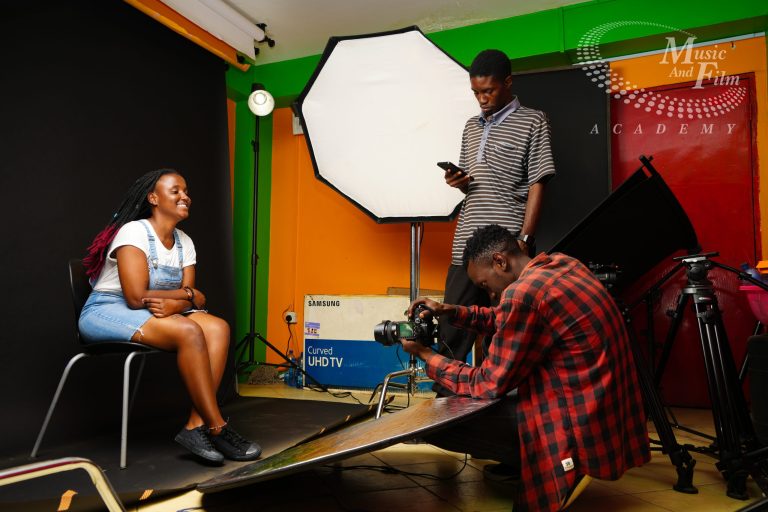 Comparing a photography vs videography career using a professional mirrorless camera setup on a tripod next to a fully rigged continuous lighting workspace at the Music And Film Academy studio in Nairobi CBD.