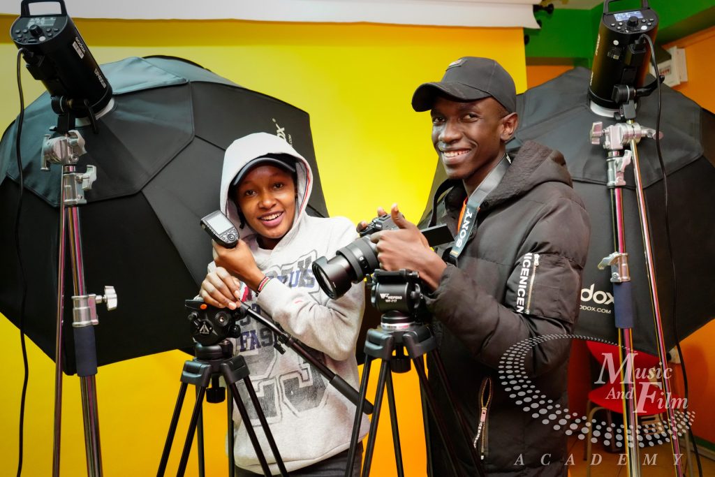 Students practicing studio flash lighting and mirrorless camera setups during a photography course in Kenya at Music and Film Academy Nairobi.